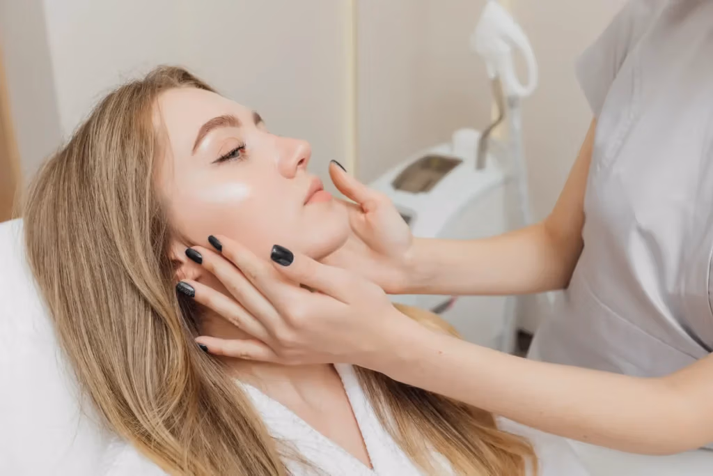 Practitioner gently holding a woman’s face while she lies on a treatment bed